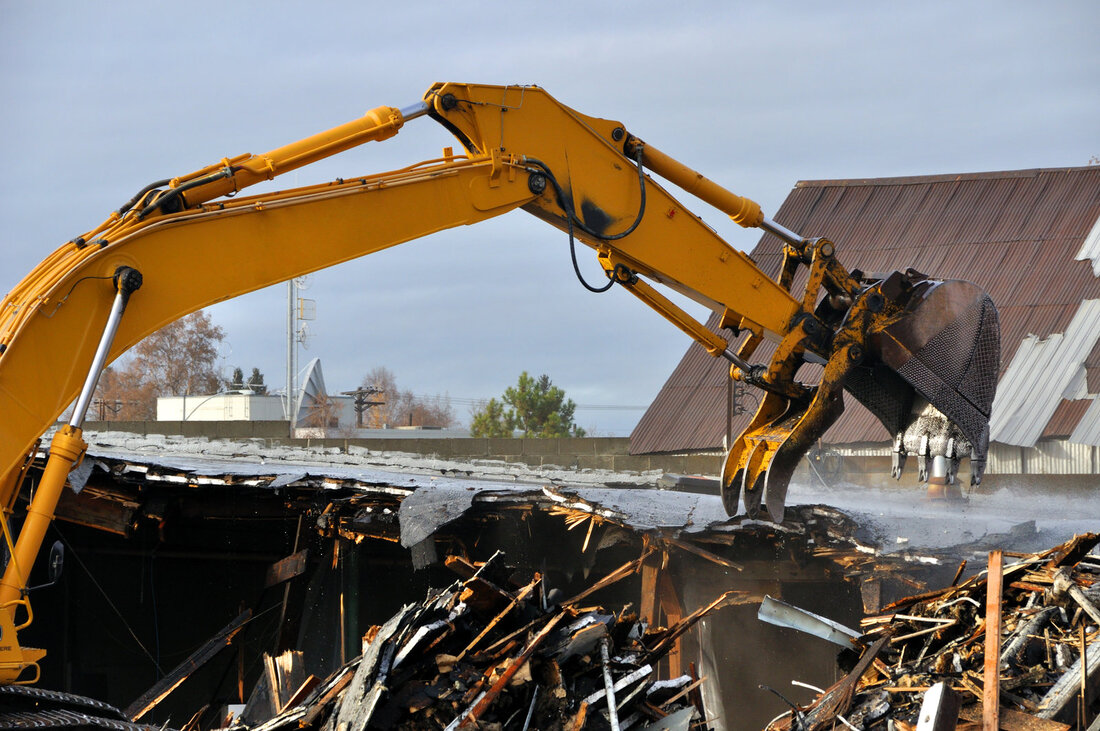 an excavator truck demolishing a barn