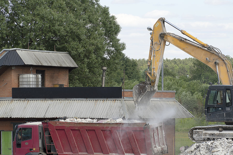 an excavator truck demolishing a garage